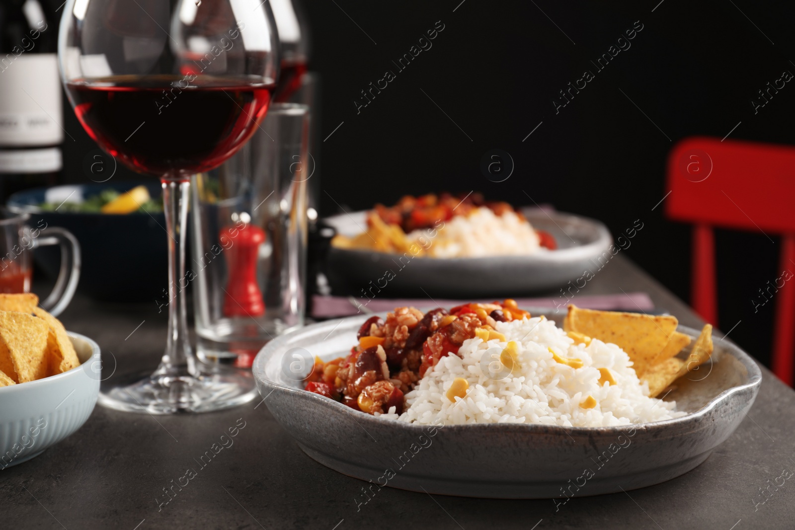 Photo of Tasty chili con carne served with rice on gray table. Dinner in restaurant