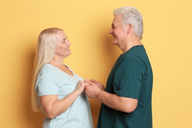 Portrait of adorable mature couple against color background