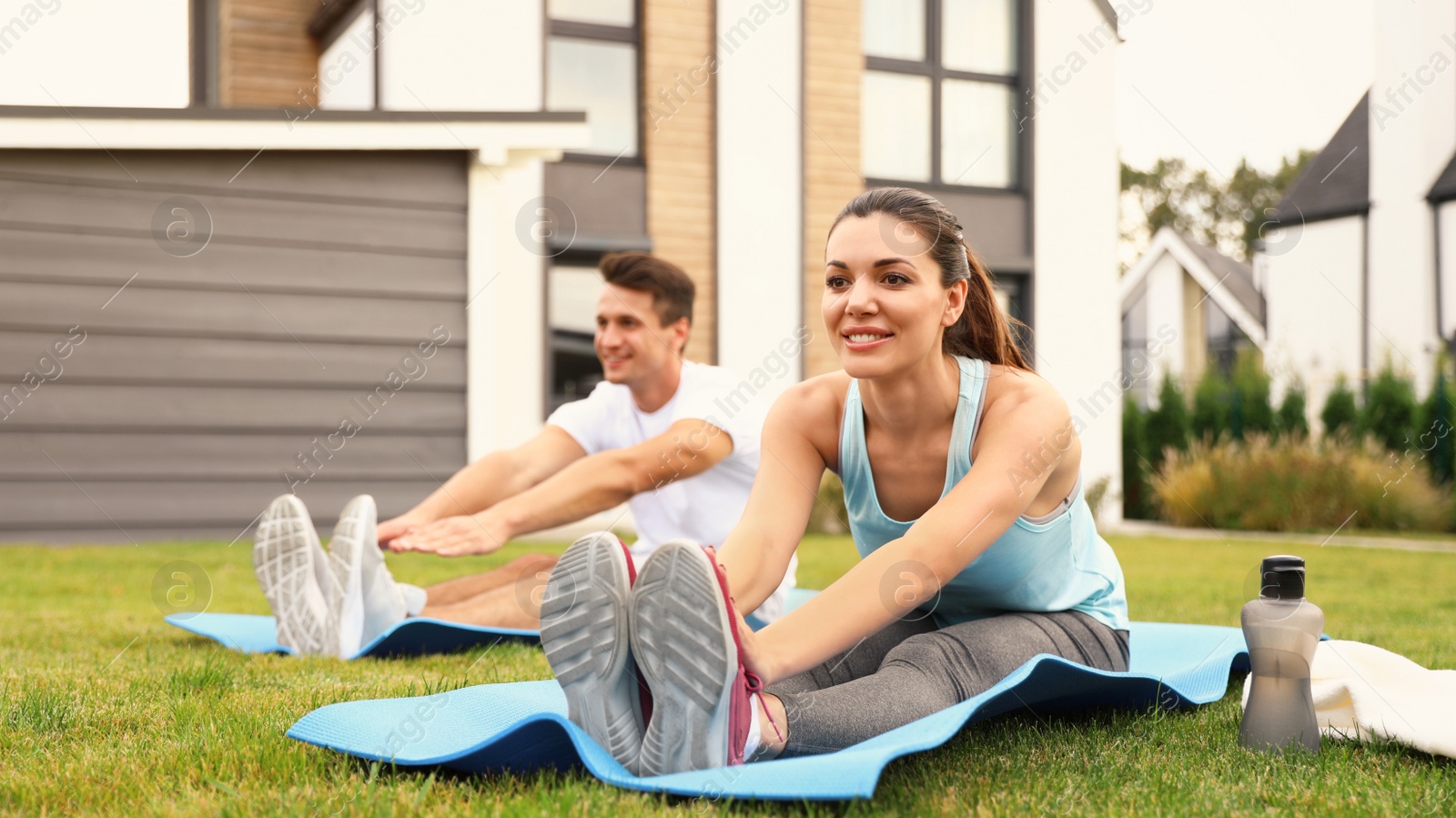 Photo of Sporty couple practicing morning yoga at backyard. Healthy lifestyle