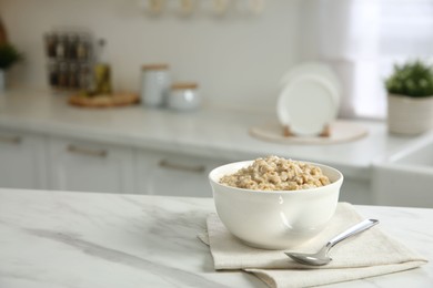 Photo of Breakfast time. Tasty oatmeal in bowl on white marble table. Space for text