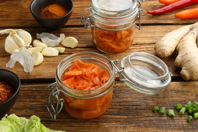 Photo of Delicious kimchi with Chinese cabbage and ingredients on wooden table