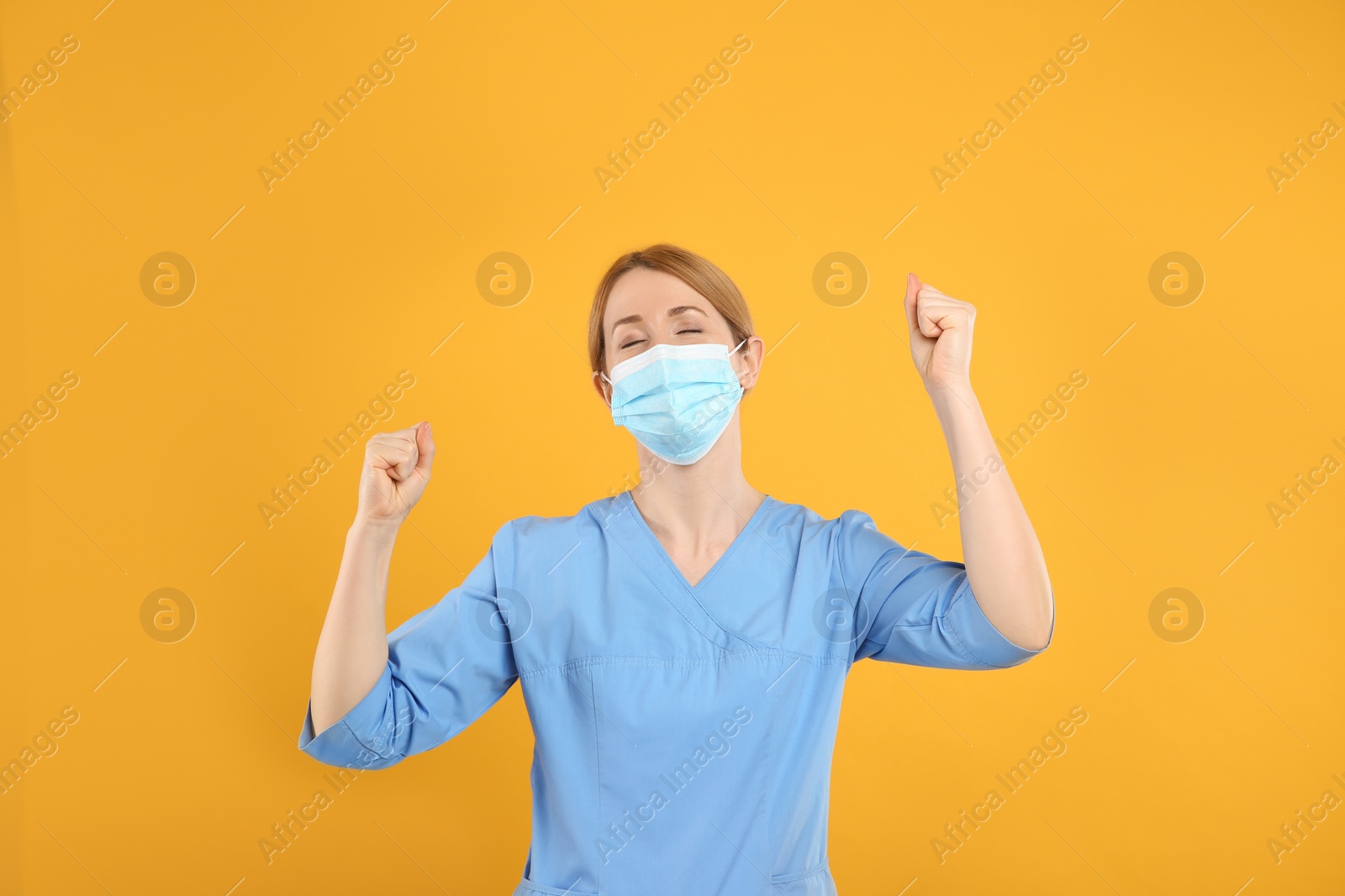 Photo of Emotional doctor with protective mask on yellow background. Strong immunity concept