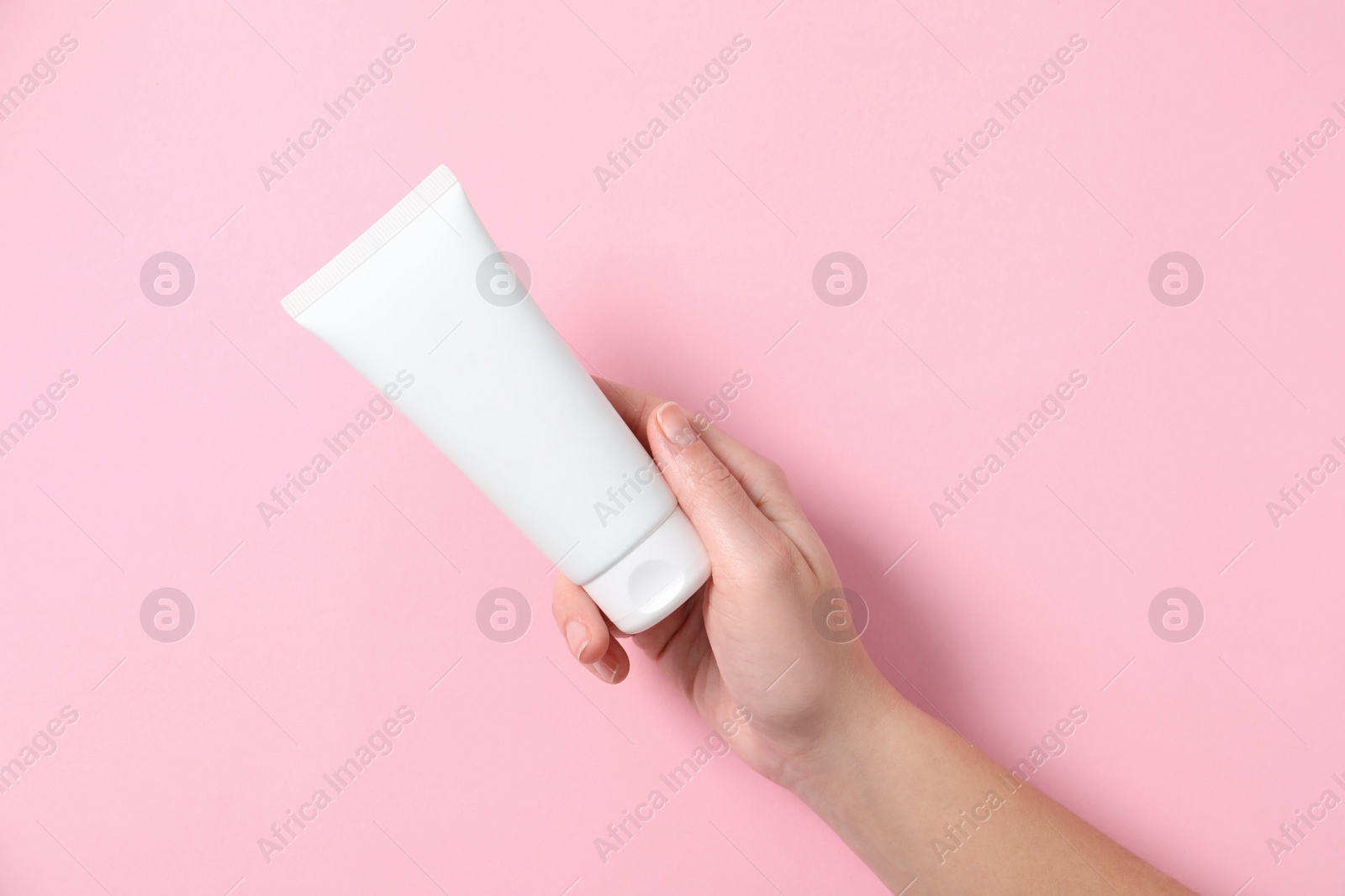 Photo of Woman with tube of hand cream on pink background, top view