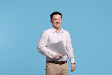 Photo of Happy man with laptop on light blue background