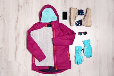 Photo of Flat lay composition with female clothes for winter vacation on wooden background