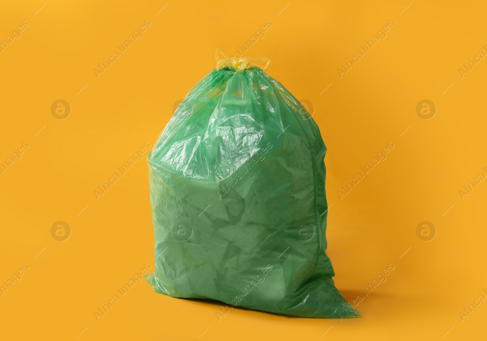 Photo of Trash bag full of garbage on yellow background