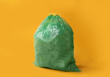 Trash bag full of garbage on yellow background