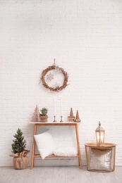 Photo of Console table with Christmas decoration near brick wall. Idea for festive interior