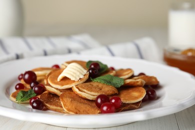 Photo of Cereal pancakes with cranberries and butter on white wooden table, closeup