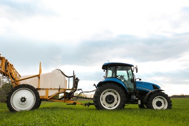 Photo of Tractor spraying pesticide in field on sunny day. Agricultural industry