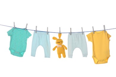 Photo of Colorful baby clothes and toy drying on laundry line against white background