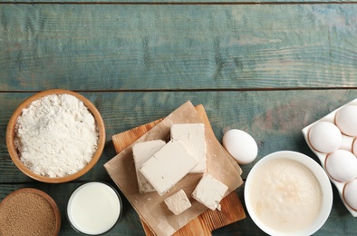 Pieces of compressed yeast and dough ingredients on blue wooden table, flat lay. Space for text