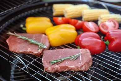Photo of Fresh steaks and vegetables on barbecue grill, closeup