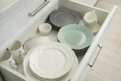 Clean plates, cups, butter dish and bowl in drawer indoors