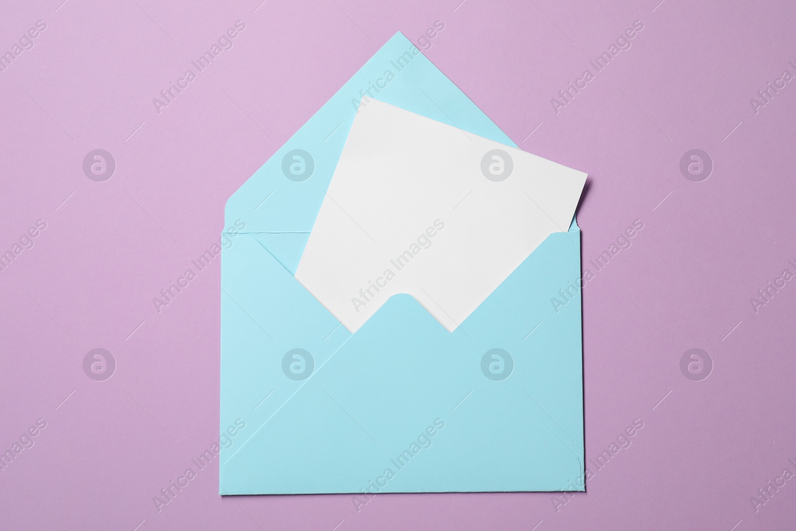 Photo of Letter envelope with card on violet background, top view