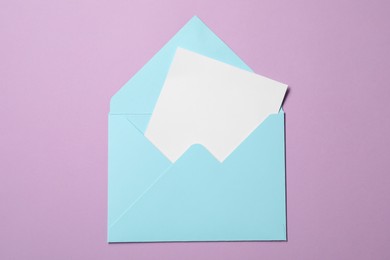 Letter envelope with card on violet background, top view