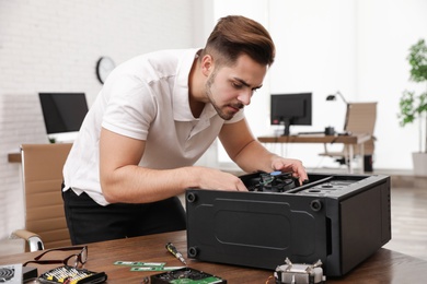 Male technician repairing computer at table indoors