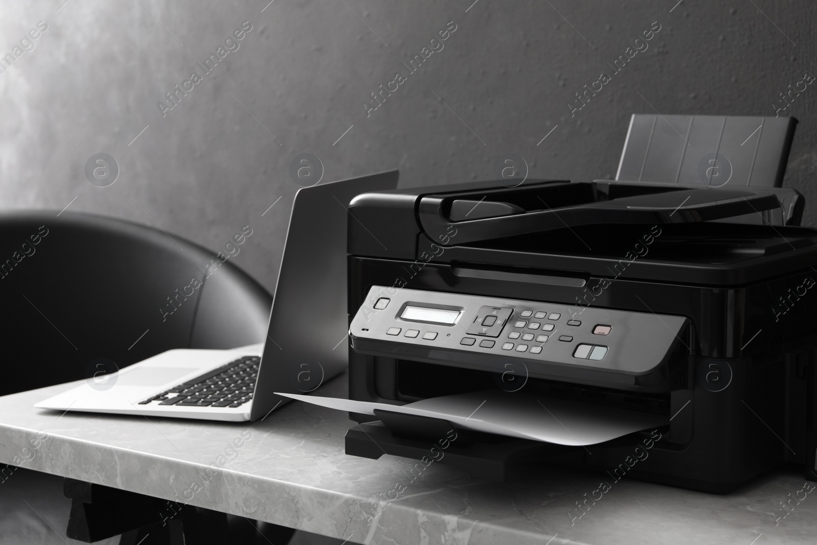 Photo of New modern printer and laptop on grey table indoors