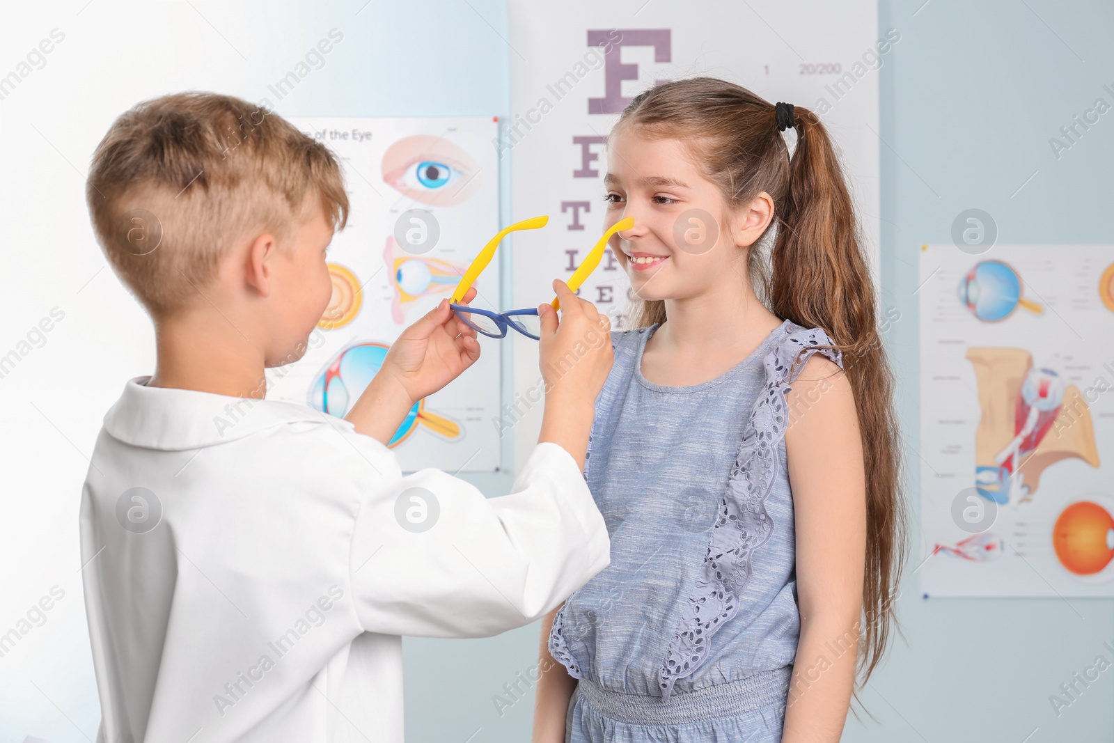 Photo of Cute little children playing doctor and patient in ophthalmologist office