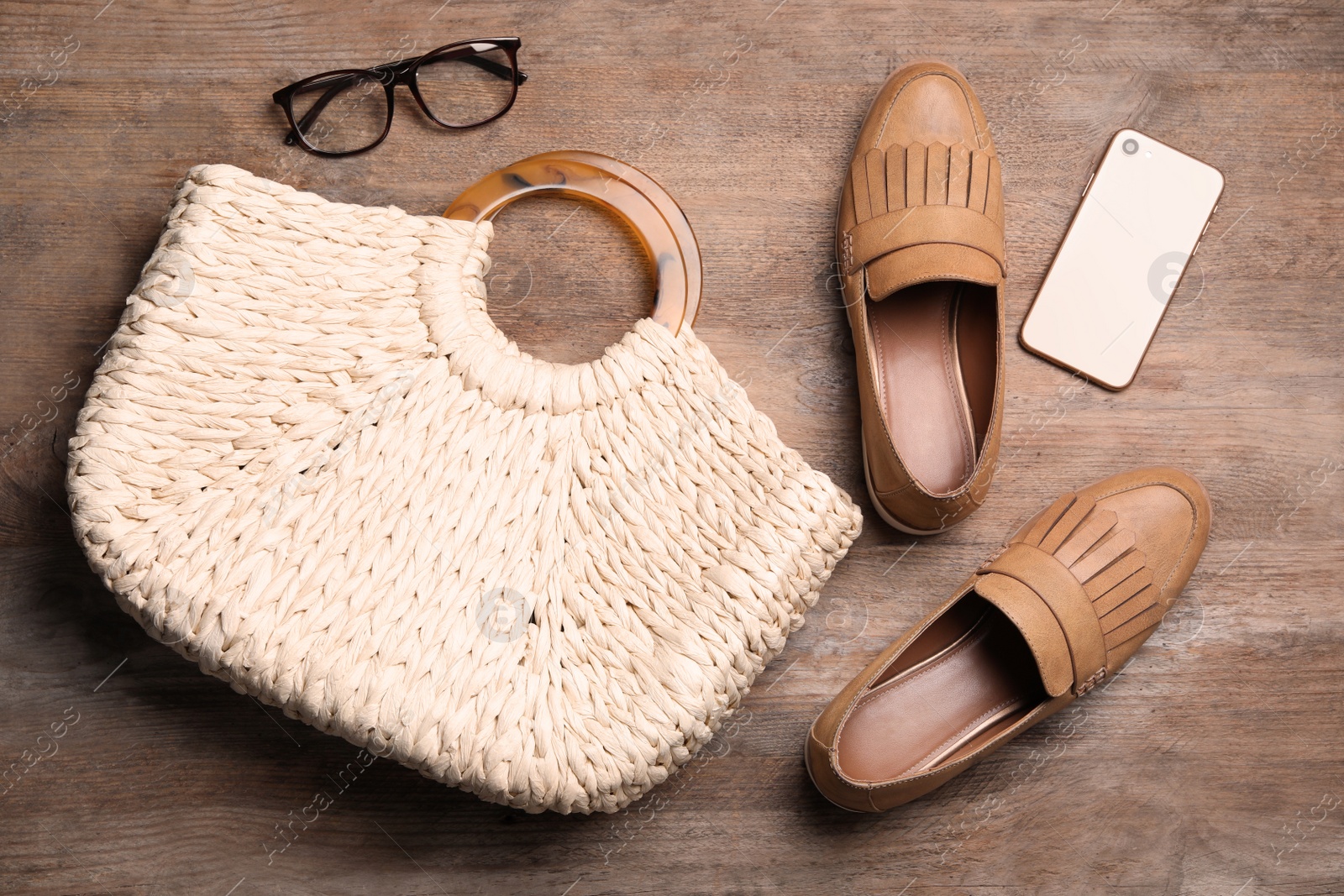 Photo of Stylish shoes, straw woman's bag and smartphone on wooden background, flat lay