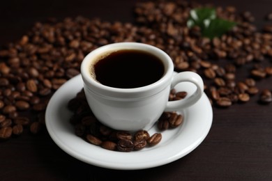 Cup of aromatic coffee and beans on wooden table