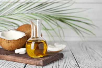 Photo of Ripe coconut and oil in bottle on wooden table. Healthy cooking