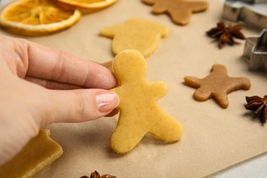 Photo of Woman holding uncooked cookie at table, closeup. Christmas biscuits