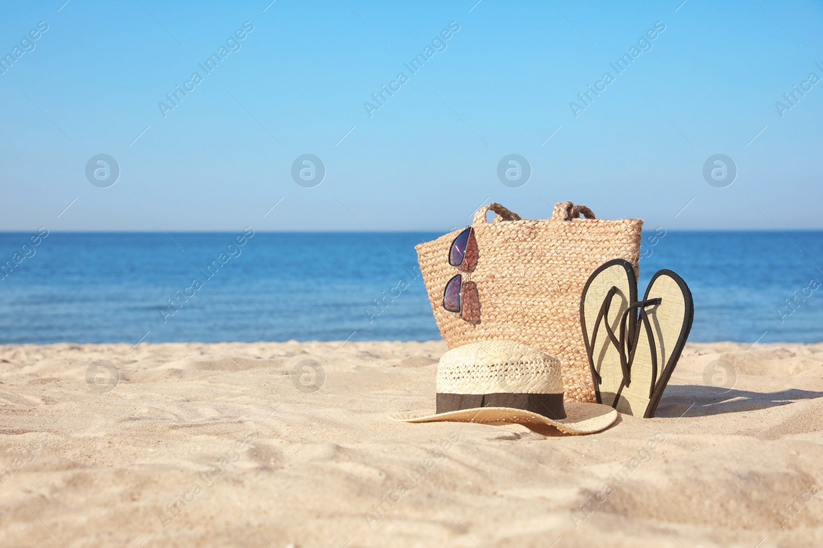 Photo of Stylish beach accessories on sandy sea shore