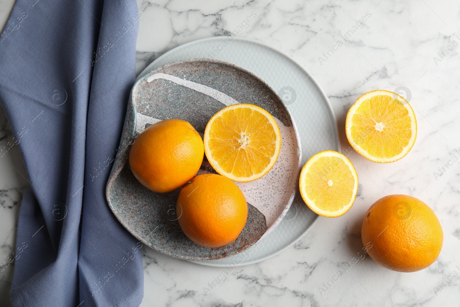 Photo of Fresh juicy oranges and plate on marble table, top view