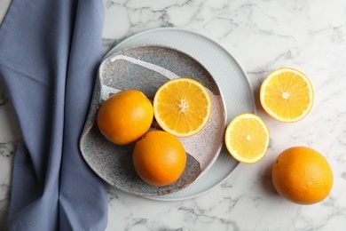 Fresh juicy oranges and plate on marble table, top view