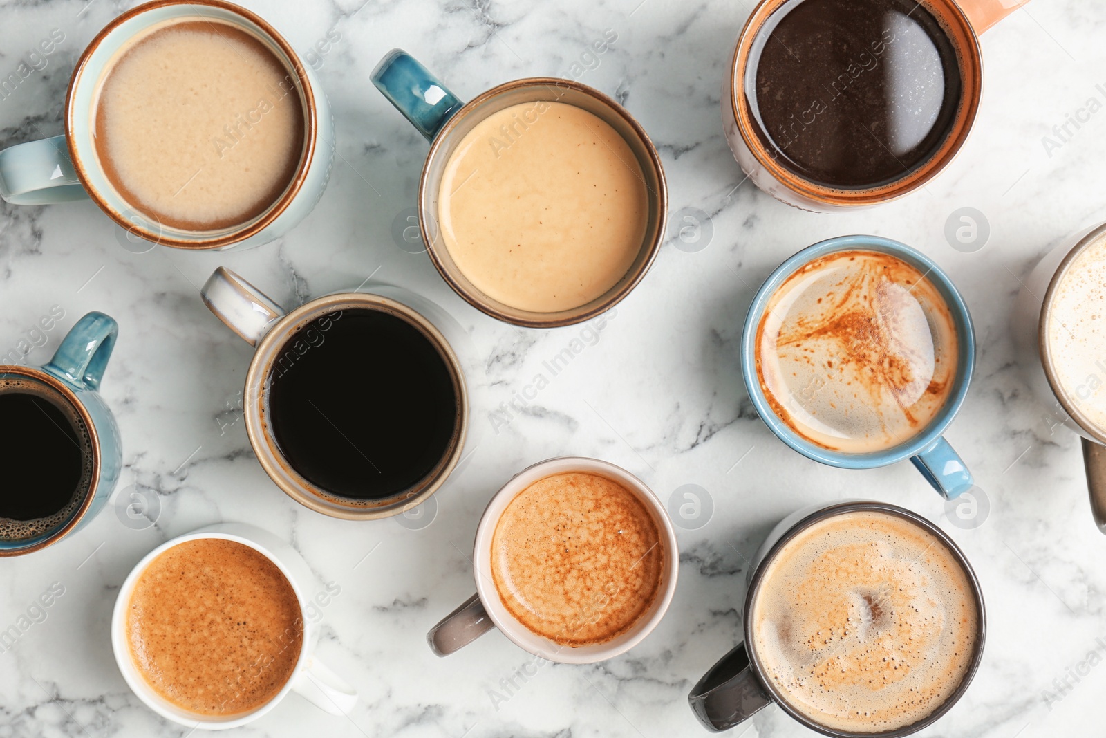 Photo of Many cups of different aromatic hot coffee on marble table