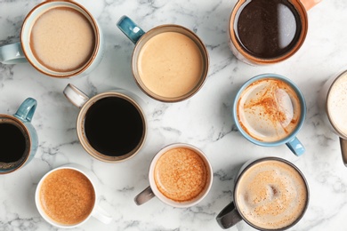 Photo of Many cups of different aromatic hot coffee on marble table