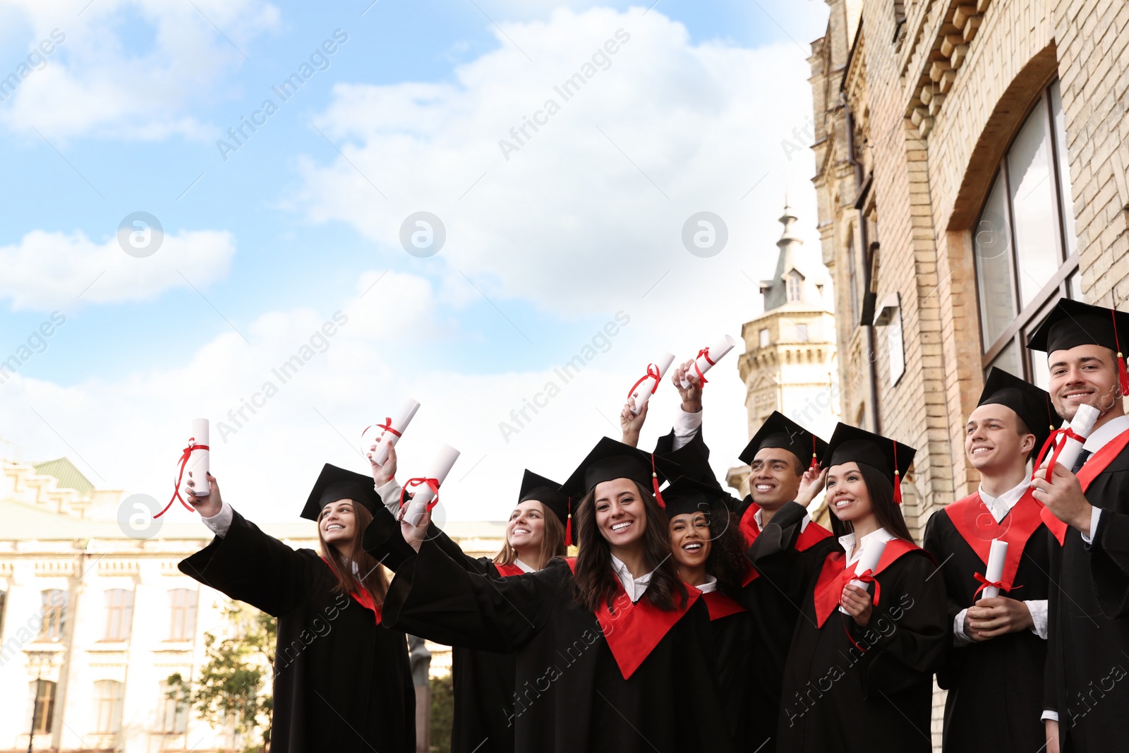 Photo of Happy students with diplomas outdoors. Graduation ceremony