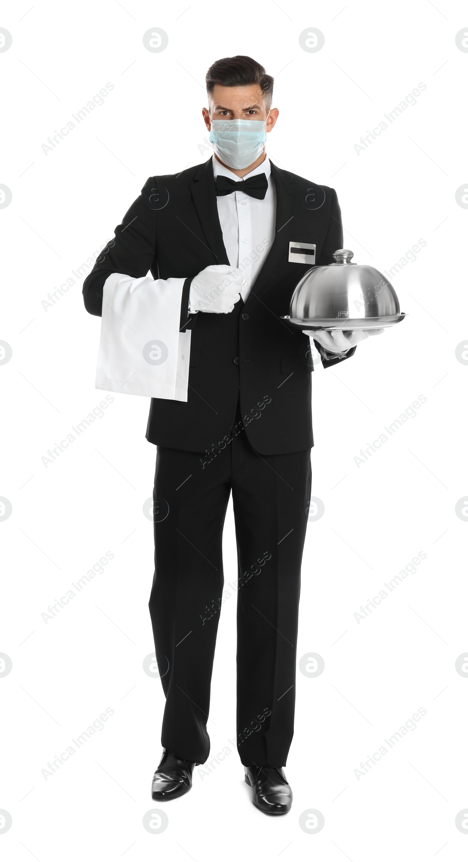 Photo of Waiter in medical face mask holding tray with lid on white background