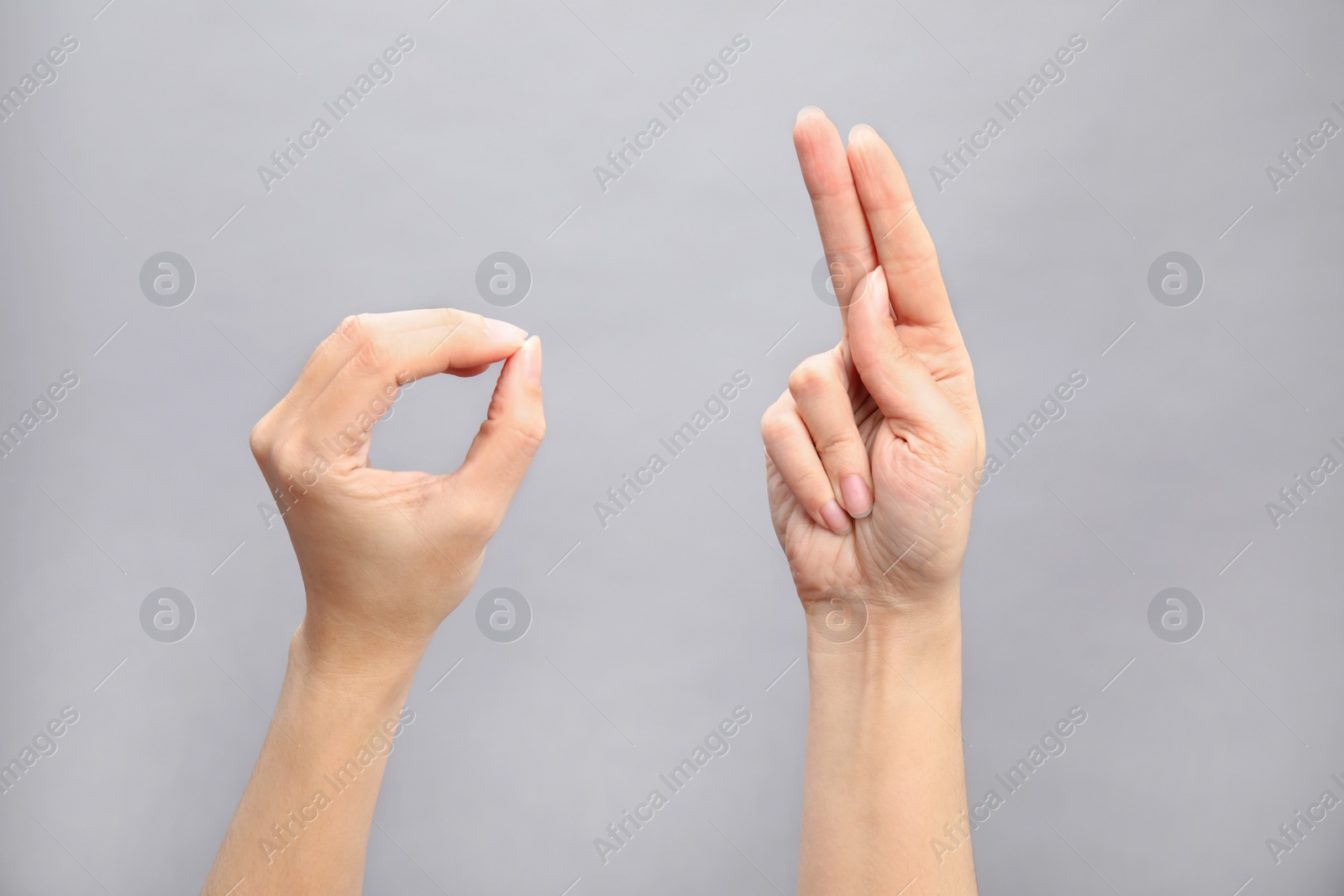 Photo of Woman showing word okay on grey background, closeup. Sign language