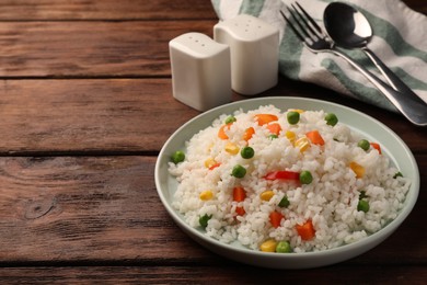 Delicious rice with vegetables on wooden table, space for text