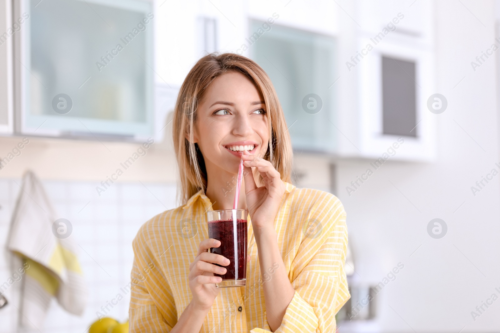 Photo of Young woman with glass of tasty healthy smoothie in kitchen