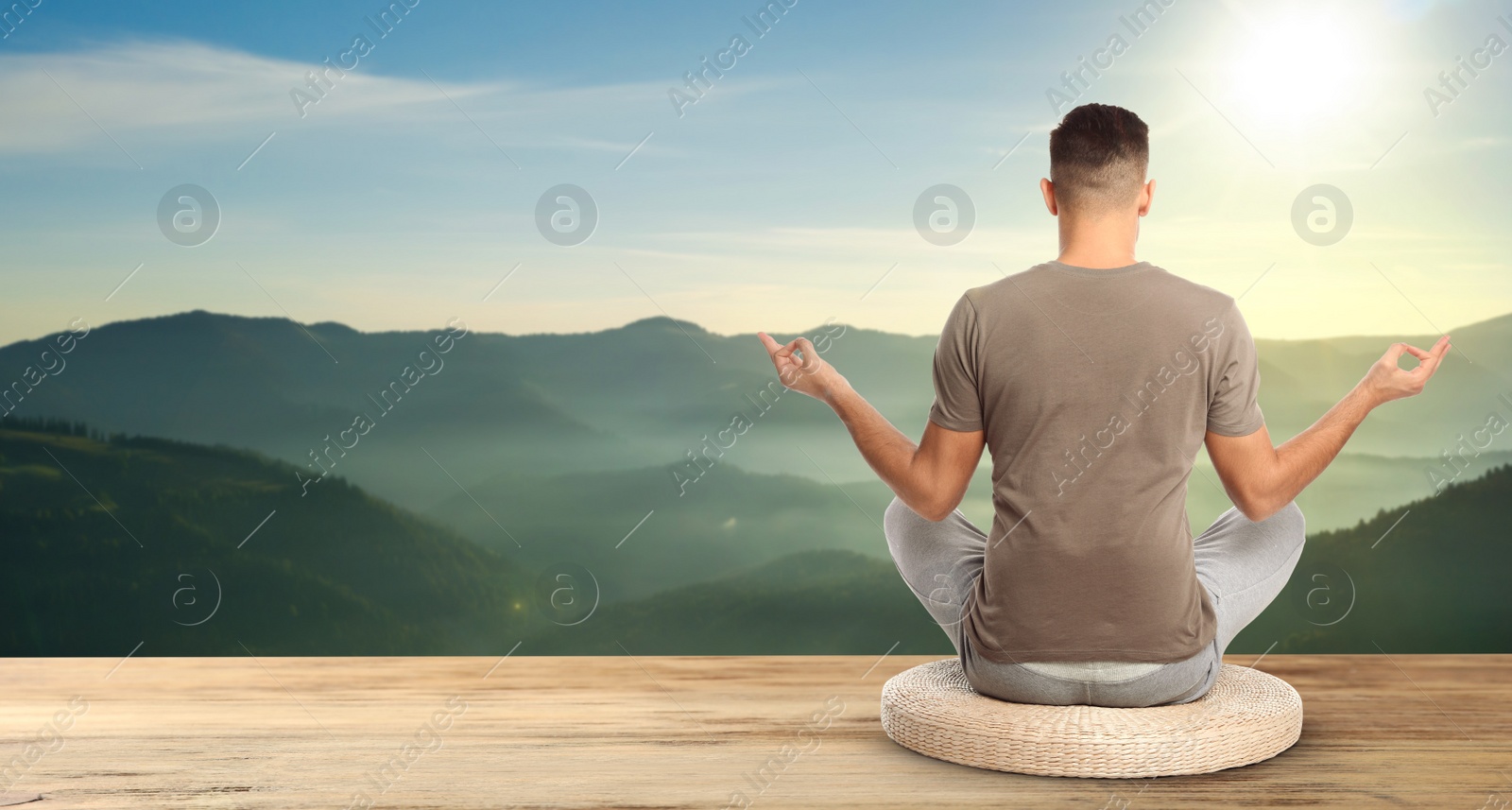 Image of Man practicing yoga on wooden surface against beautiful mountain landscape, space for text. Banner design