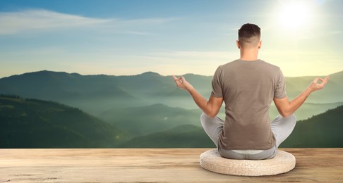 Man practicing yoga on wooden surface against beautiful mountain landscape, space for text. Banner design