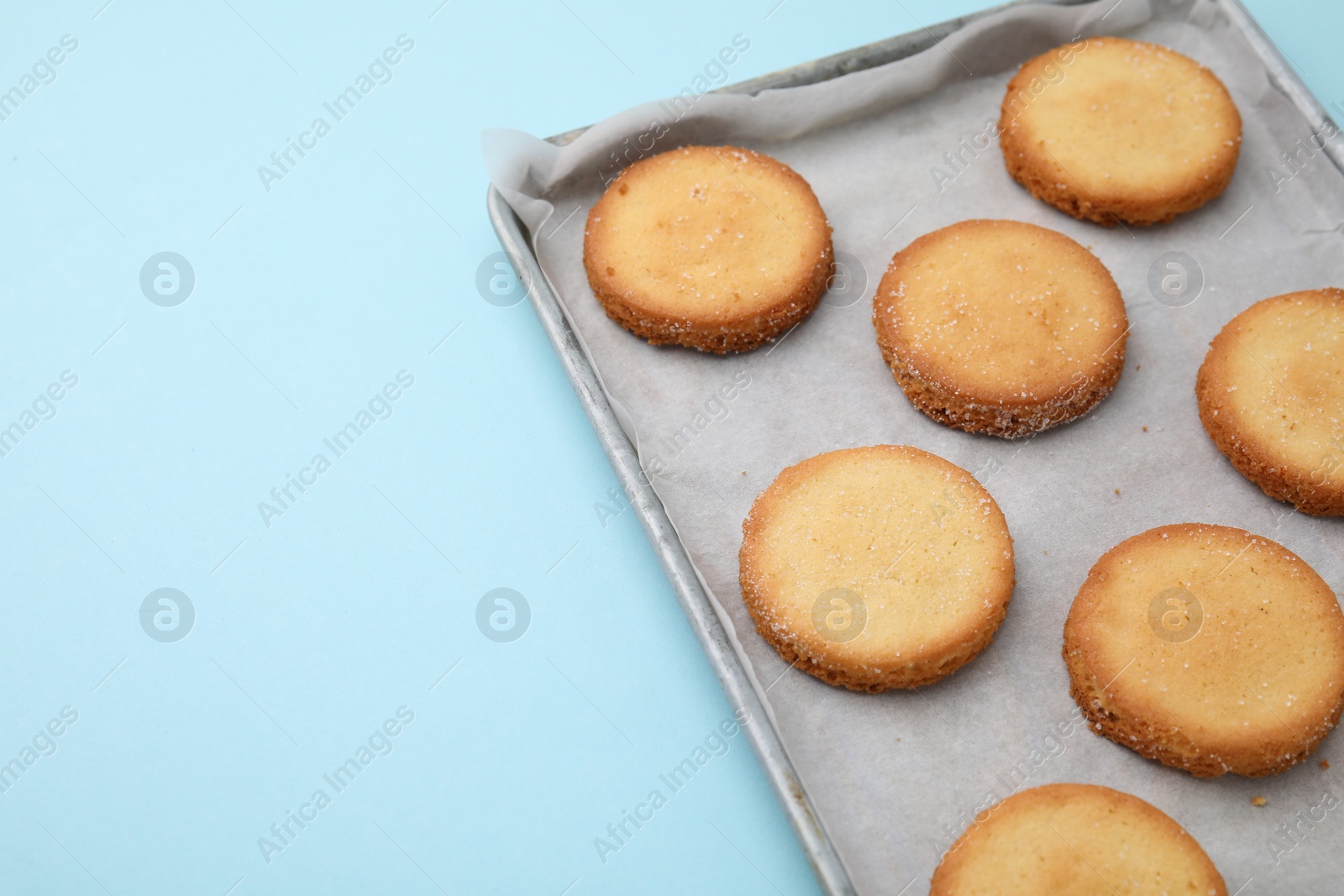 Photo of Tray with tasty sweet sugar cookies on light blue background, closeup. Space for text