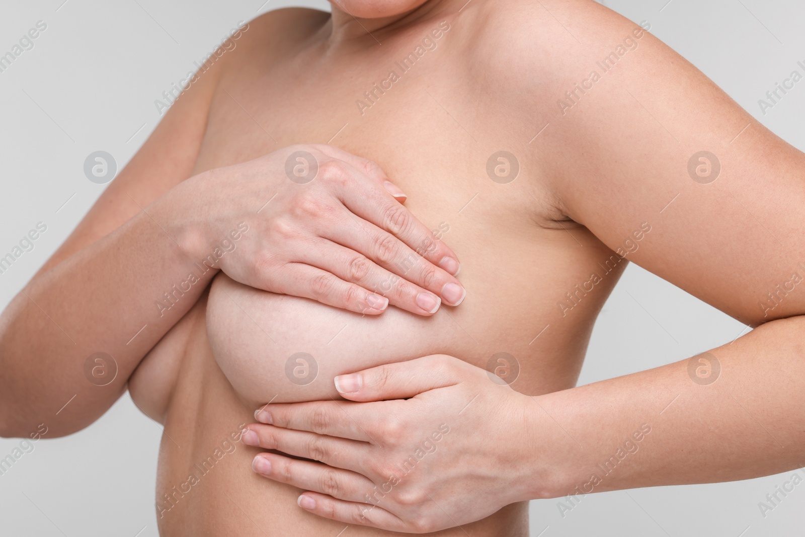 Photo of Mammology. Naked woman doing breast self-examination on light grey background, closeup