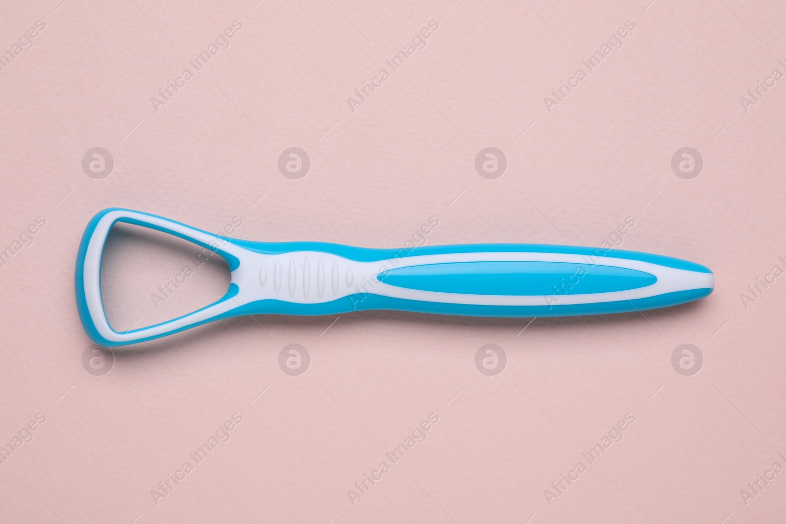 Photo of One light blue tongue cleaner on pink background, top view. Dental care