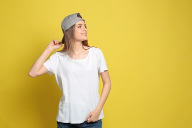 Young woman wearing blank t-shirt on yellow background. Mockup for design