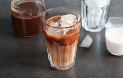 Photo of Glass with cold brew coffee and milk on table