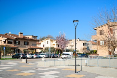 Beautiful city square with street lights surrounded by cars and houses on sunny day