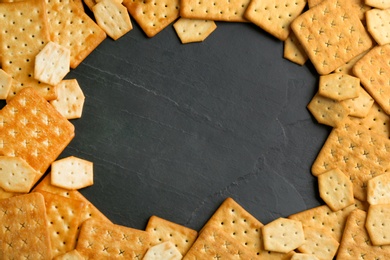 Photo of Frame of delicious crackers on black background, flat lay. Space for text