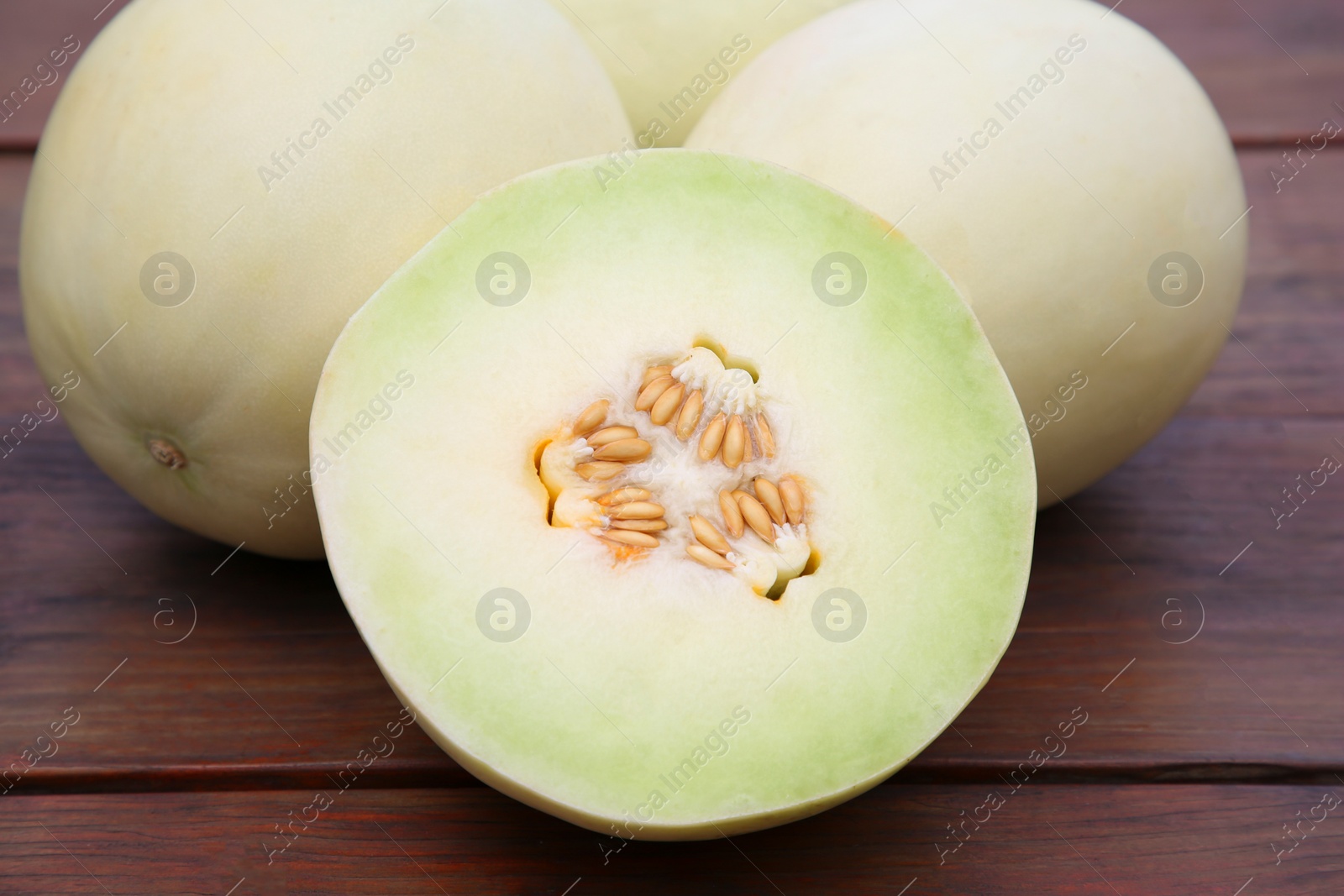 Photo of Whole and cut fresh ripe melons on wooden table, closeup