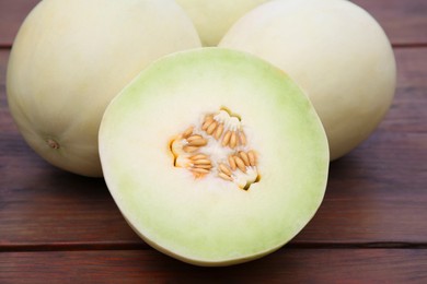 Photo of Whole and cut fresh ripe melons on wooden table, closeup