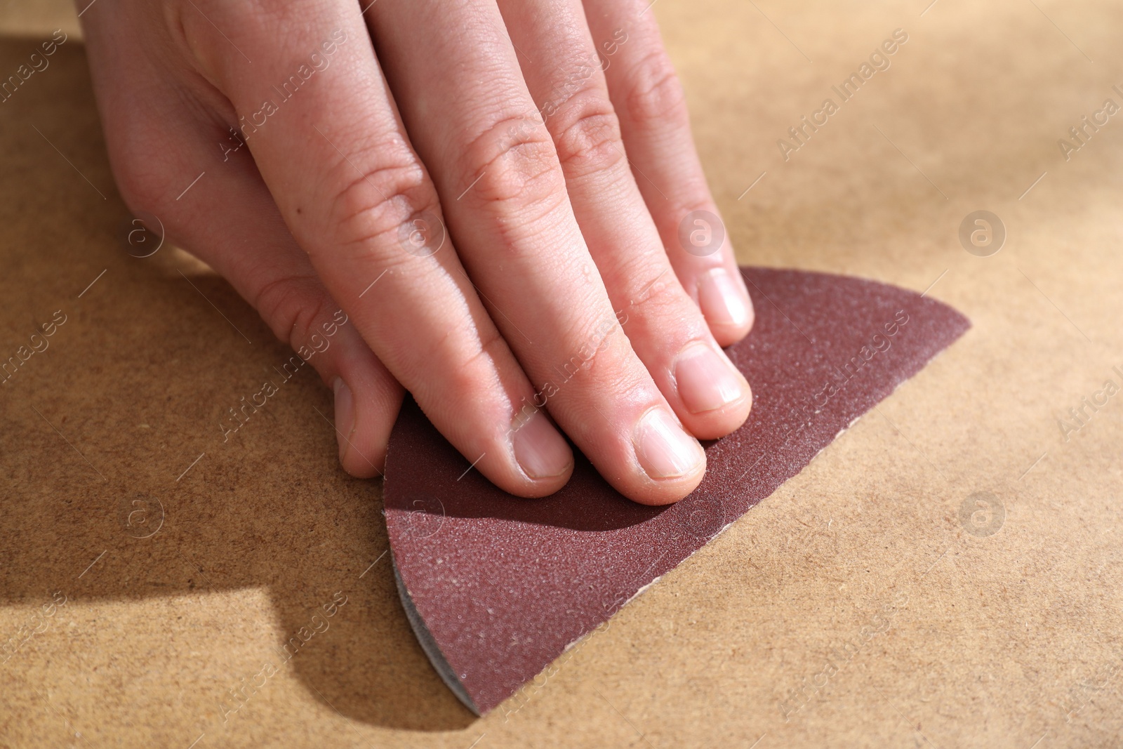 Photo of Man polishing wooden table with sandpaper, closeup