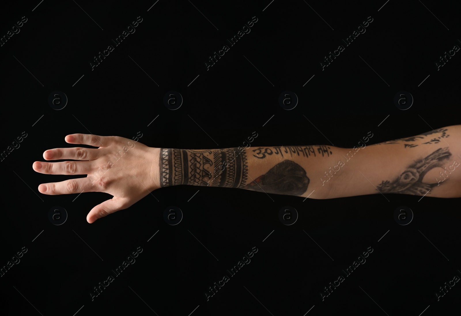 Photo of Woman with stylish tattoos on arm against black background, closeup